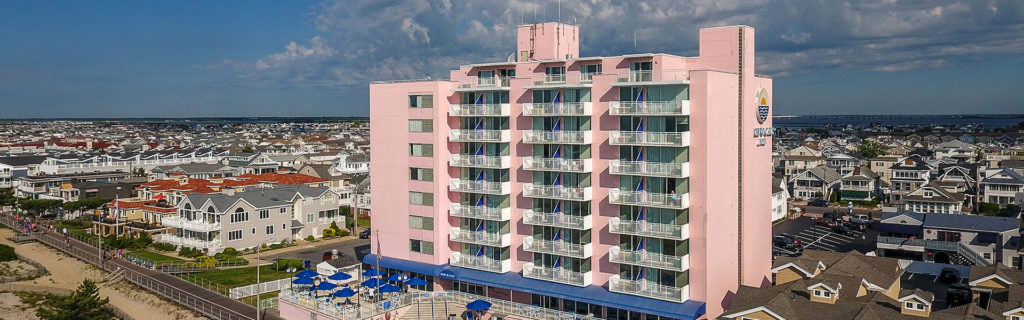 An aerial view of the Port-O-Call Hotel, a beautiful pink building directly on the shore