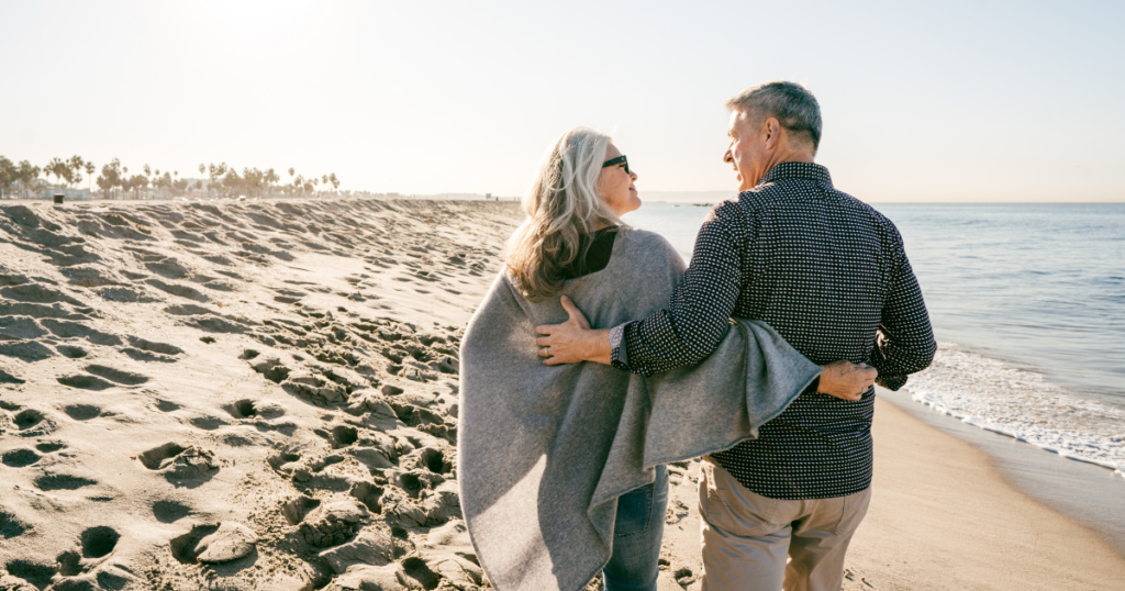 A couple walking together and smiling at each other on a beach