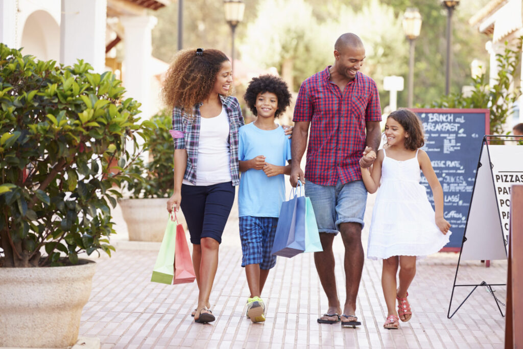 Parents and two kids walking down a shopping street